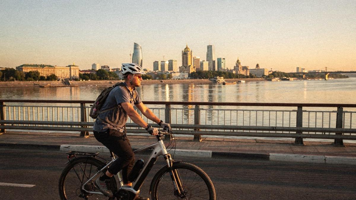 E-bike rider crossing a Dnipro bridge in Kyiv at golden hour